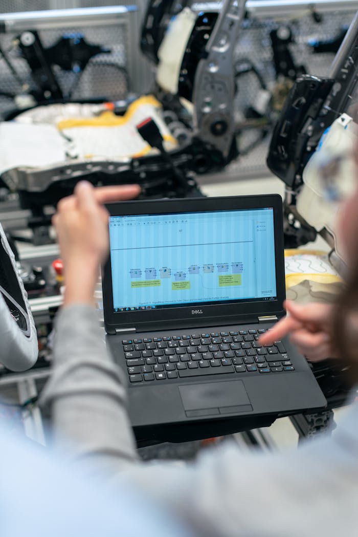 about-04 Engineers using a laptop to analyze software data in an industrial workshop setting.